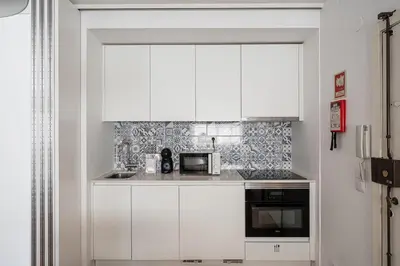 a white kitchen with white cabinets and a microwave at GuestReady - Oporto Vintage in Porto