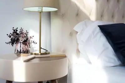 a white bed with a table with a vase of flowers on it at O Herculano Porto in Porto