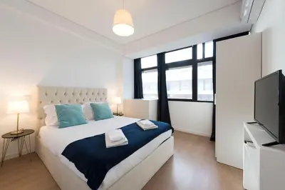 a bedroom with a large bed and a flat screen tv at O Herculano Porto in Porto
