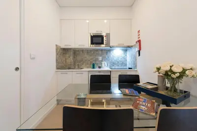 a kitchen with white cabinets and a table with flowers at O Herculano Porto in Porto