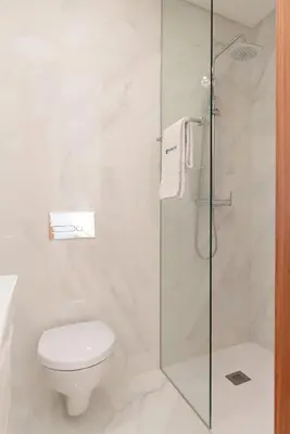 a bathroom with a toilet and a glass shower at Host Wise - Bright and Cozy House with Dom Luís Bridge View in Porto