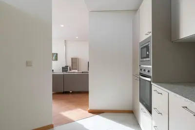 a kitchen with white cabinets and a stove top oven at Host Wise - Bright and Cozy House with Dom Luís Bridge View in Porto