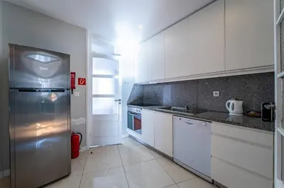 a kitchen with white cabinets and a stainless steel refrigerator at Large and Charming Apartment Downtown in Porto