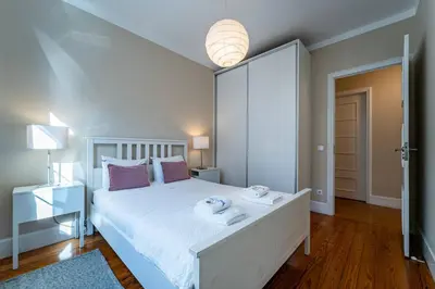 a bedroom with a white bed with two towels on it at Large and Charming Apartment Downtown in Porto