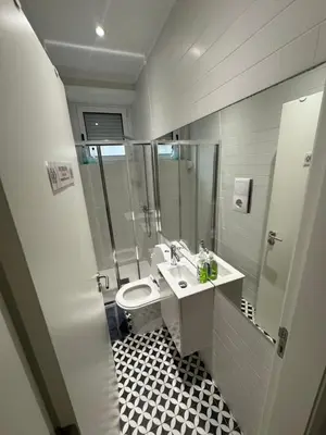 a bathroom with a toilet and a sink and a shower at Dormitório Aliados in Porto