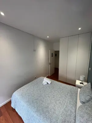 a bedroom with a bed and a white wall at Dormitório Aliados in Porto