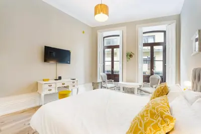 a bedroom with a white bed and a desk with a tv at GuestReady - Alegria Guesthouse in Porto