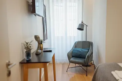 a room with a chair and a table and a lamp at 24 Agosto Amazing Triplex by Vacationy in Porto