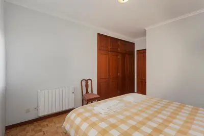 a white bedroom with a bed and a chair at Guilhermina's Place in Vila Nova de Gaia