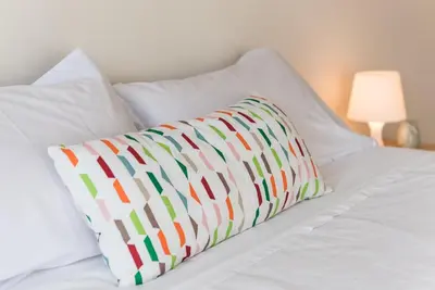 a white bed with a colorful pillow on it at GuestReady - Even Flow Flat in Porto