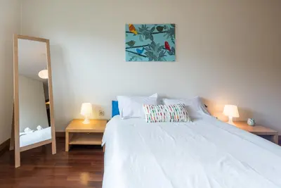 a bedroom with a white bed with two tables and a mirror at GuestReady - Even Flow Flat in Porto