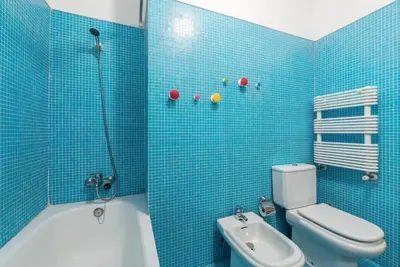 a blue tiled bathroom with a toilet and a shower at GuestReady - Even Flow Flat in Porto