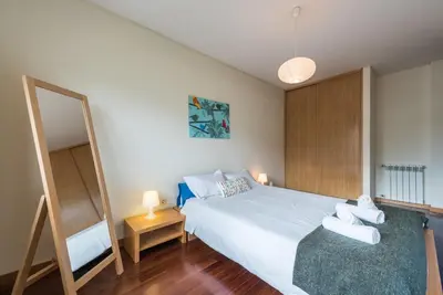 a bedroom with a large white bed and a mirror at GuestReady - Even Flow Flat in Porto