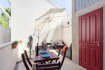 a red door on a patio with a table and chairs at Host Wise - Spacious Bright Flat - Terrace in Porto