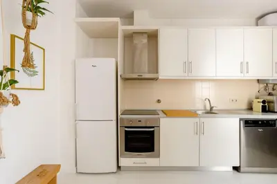 a kitchen with white cabinets and a white refrigerator at Sunny Priorado Vintage studio with balcony in Porto
