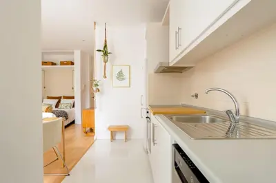 a white kitchen with a sink and a living room at Sunny Priorado Vintage studio with balcony in Porto