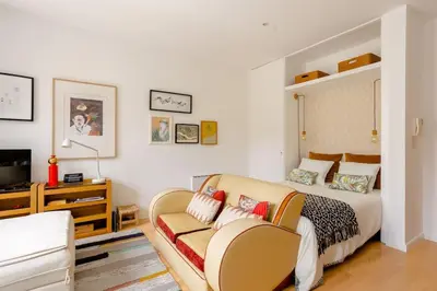 a bedroom with a bed and a couch and a tv at Sunny Priorado Vintage studio with balcony in Porto