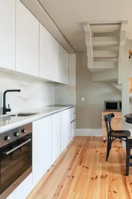 a kitchen with white cabinets and a black chair at Host Wise - Modern Design Duplex w Balcony in Porto