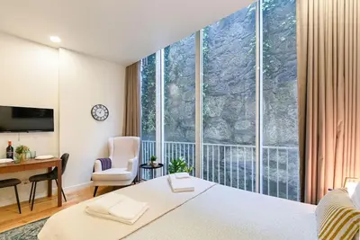 a bedroom with a bed and a desk and a large window at Santa Catarina Oporto City Center in Porto
