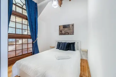 a bedroom with a white bed with blue curtains at Charming 2BR w Terrace & Garden in Porto
