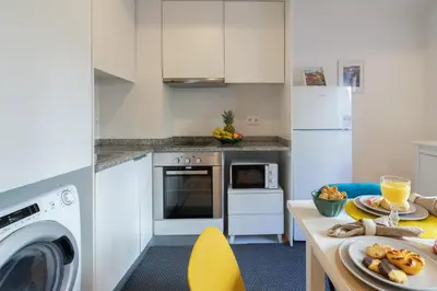 a kitchen with white cabinets and a table with a dishwasher at Host Wise - Sunny Bright Duplexes & Pool in Vila Nova de Gaia