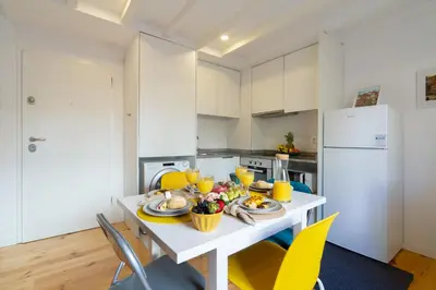a kitchen with a white table and yellow chairs at Host Wise - Sunny Bright Duplexes & Pool in Vila Nova de Gaia