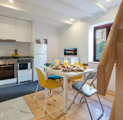 a kitchen with a table and chairs with food on it at Host Wise - Sunny Bright Duplexes & Pool in Vila Nova de Gaia