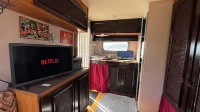 an rv living room with a television and a kitchen at Caravan Experience in Santa Justa