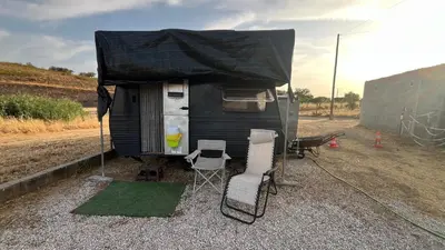 a black camper with a tent and two chairs at Caravan Experience in Santa Justa