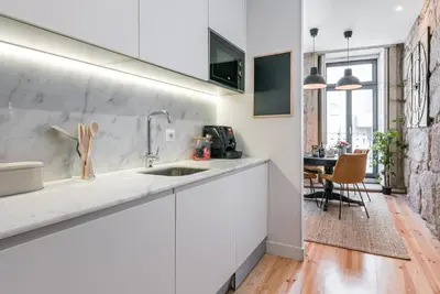 a white kitchen with a sink and a table at GuestReady - Industrial stay in downtown Porto in Porto