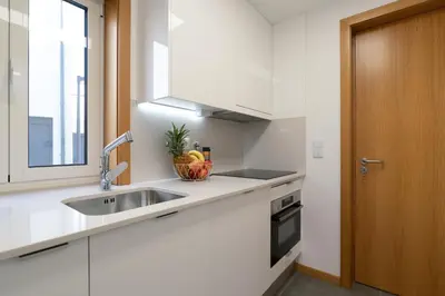 a white kitchen with a sink and a window at Host Wise - Elegant Home in the Heart of Porto in Porto