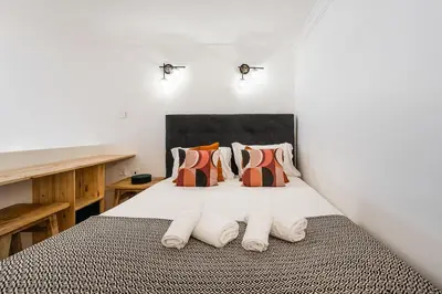 a bedroom with a bed with white sheets and pillows at GuestReady - Mezzanine comfort in Porto in Porto