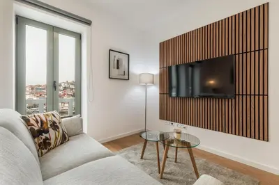 a living room with a couch and a tv on a wall at Douro's Bridge View - Swimming pool in Vila Nova de Gaia