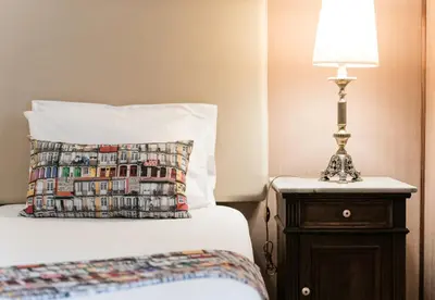 a bed with a pillow and a lamp on a night stand at Office Suits in Flores by D&S in Porto