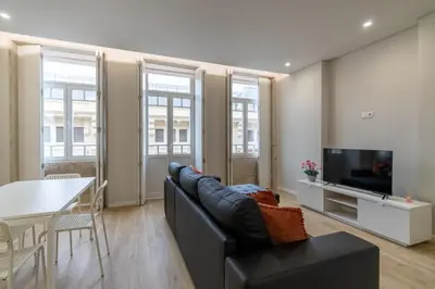 a living room with a couch and a tv and a table at Bolhão Market Apartment in Porto