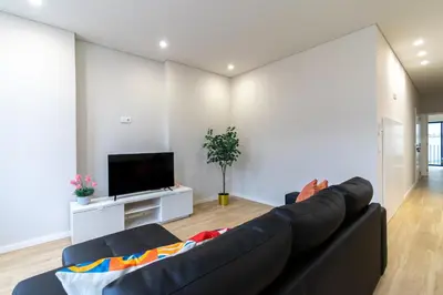 a living room with a black couch and a tv at Bolhão Market Apartment in Porto