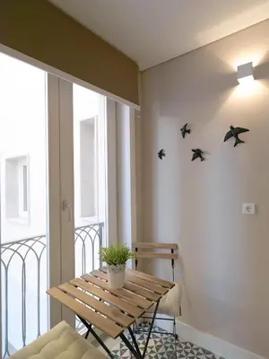 a balcony with a wooden table and birds on the wall at New Oporto Apartments - Cardosas in Porto
