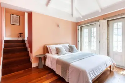 a bedroom with a bed with white sheets and orange walls at Superb Apartment in the HEART of Historical Center in Porto