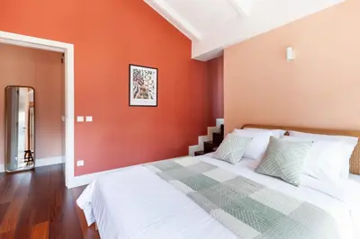 a bedroom with a bed with an orange wall at Superb Apartment in the HEART of Historical Center in Porto