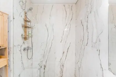 a bathroom with a shower with white marble walls at City-Center Apartments with Mezzanine and Terrace in Porto