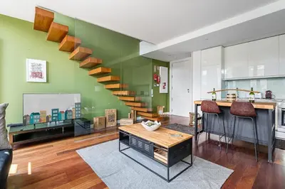 a living room with a green wall with a staircase at City-Center Apartments with Mezzanine and Terrace in Porto