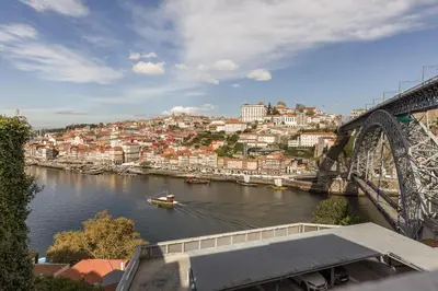 a boat in a river with a bridge at Douro's Balcony View - Swimming pool in Vila Nova de Gaia