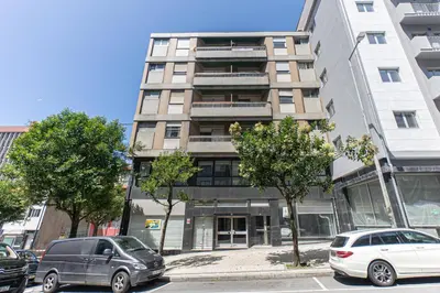 two cars parked in front of a tall building at Now Trindade in Porto