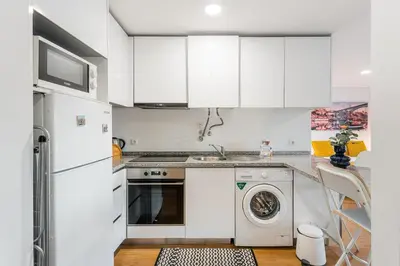 a kitchen with white cabinets and a washer and dryer at GuestReady - Homey experience in Porto in Porto