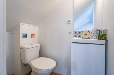 a white bathroom with a toilet and a window at Essence Oporto Apartment Downtown in Porto