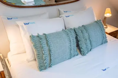 a white bed with white pillows and a green pillow at Essence Oporto Apartment Downtown in Porto