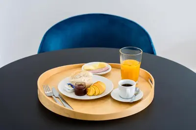 a tray with a plate of food and a glass of orange juice at Feel Porto Lapa Collection Flats in Porto