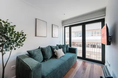 a living room with a green couch and a window at GuestReady - Silk Factory Studios and Apartments in Porto