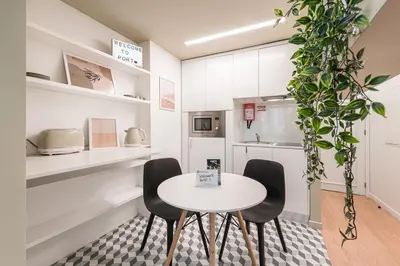 a white kitchen with a table and chairs at GuestReady - Fabric Porto Apartment in Porto