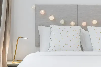 a bed with white pillows and a headboard with lights at GuestReady - Fabric Porto Apartment in Porto